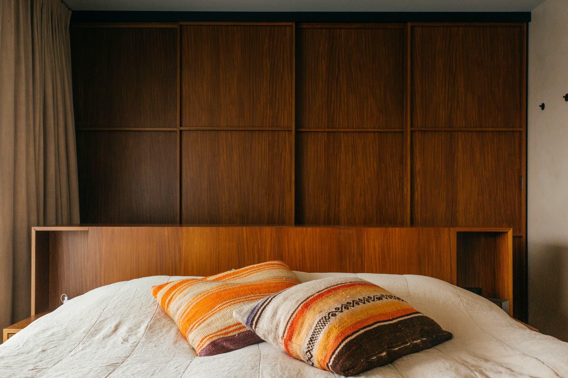 Slaapkamer met houten kastenwand en gestreepte kussens