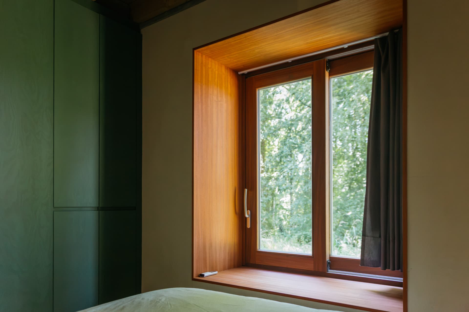 Slaapkamer met groene kasten en houten raamnis